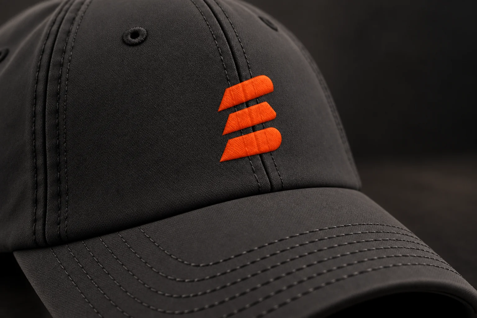 Charcoal Buildside baseball cap with an orange stacks mark and curved brim, close-up view