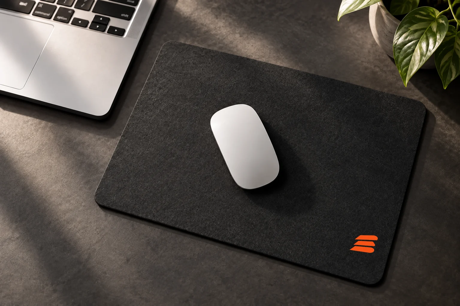 Charcoal Buildside mouse pad with an orange stacks mark beside a laptop
