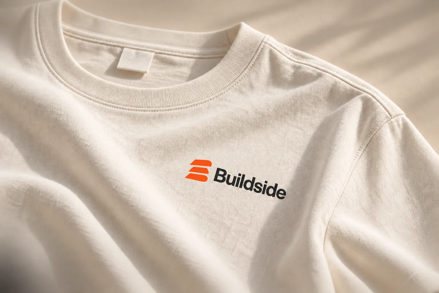 Natural-colored Buildside T-shirt with an orange and black chest logo, close-up view